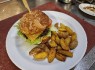 27. 150g Hovězí burger s čedarem, karamelizovanou cibulí a smažený brambor ve slupce