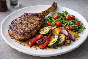 14) Vepřový tomahawk steak s grilovanou zeleninou, rukolou a cherry rajčátky 