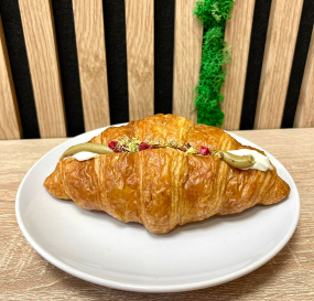 Croissant plněný pistáciovým krémem sypaný sekanými pistáciemi a sušenými malinami
